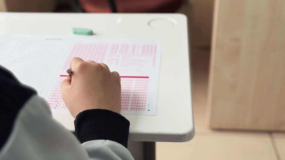 Student answering a test in a classroom, reviewing lesson materials