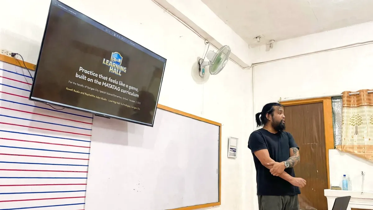 Learning Hall founder Rowil Ruelo presenting to the SCSSES faculty, with the title slide on the classroom TV