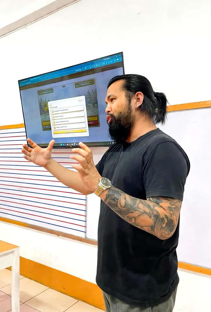 Learning Hall founder Rowil Ruelo explaining an in-game quiz shown on the classroom TV screen